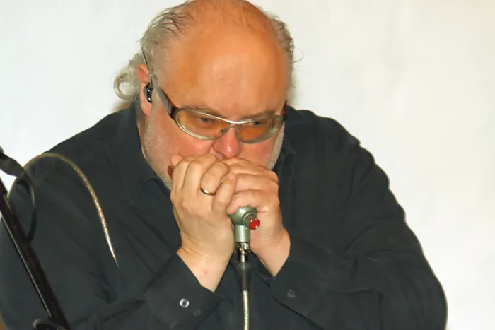 Chris Kramer spielt Mundharmonika an einem Mikrofon.