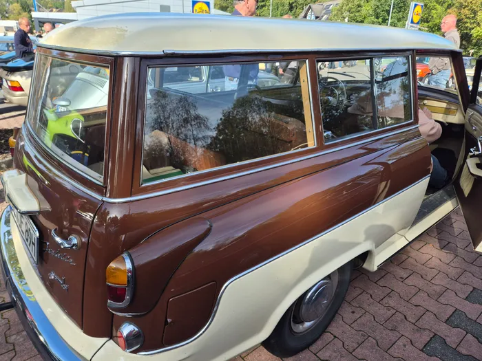 Ein braun-cremefarbener Oldtimer-Kombi auf einem gepflasterten Parkplatz.