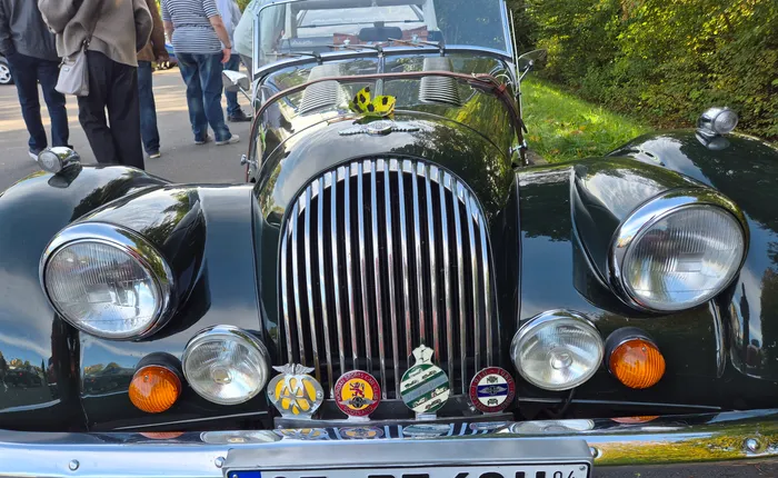 Frontansicht eines dunkelgrünen Oldtimers mit markantem Chromgrill, runden Scheinwerfern und mehreren Abzeichen.