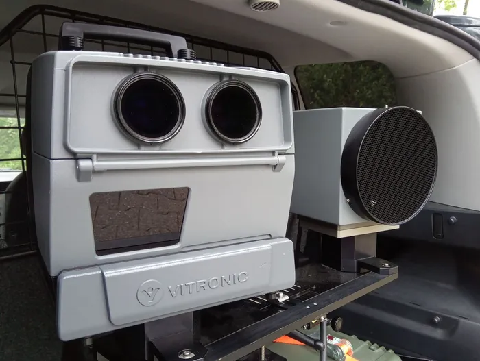 Graues Vitronic-Radargerät mit zwei Linsen und einem Display, montiert im Innenraum eines Fahrzeugs.