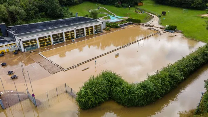 Das Gelände des Hallen- und Freibads in Altena-Dahle ist nach dem Hochwasser im Juli 2021 vollständig überflutet. Das Wasser bedeckt das Schwimmbecken und reicht bis an das Gebäude heran.