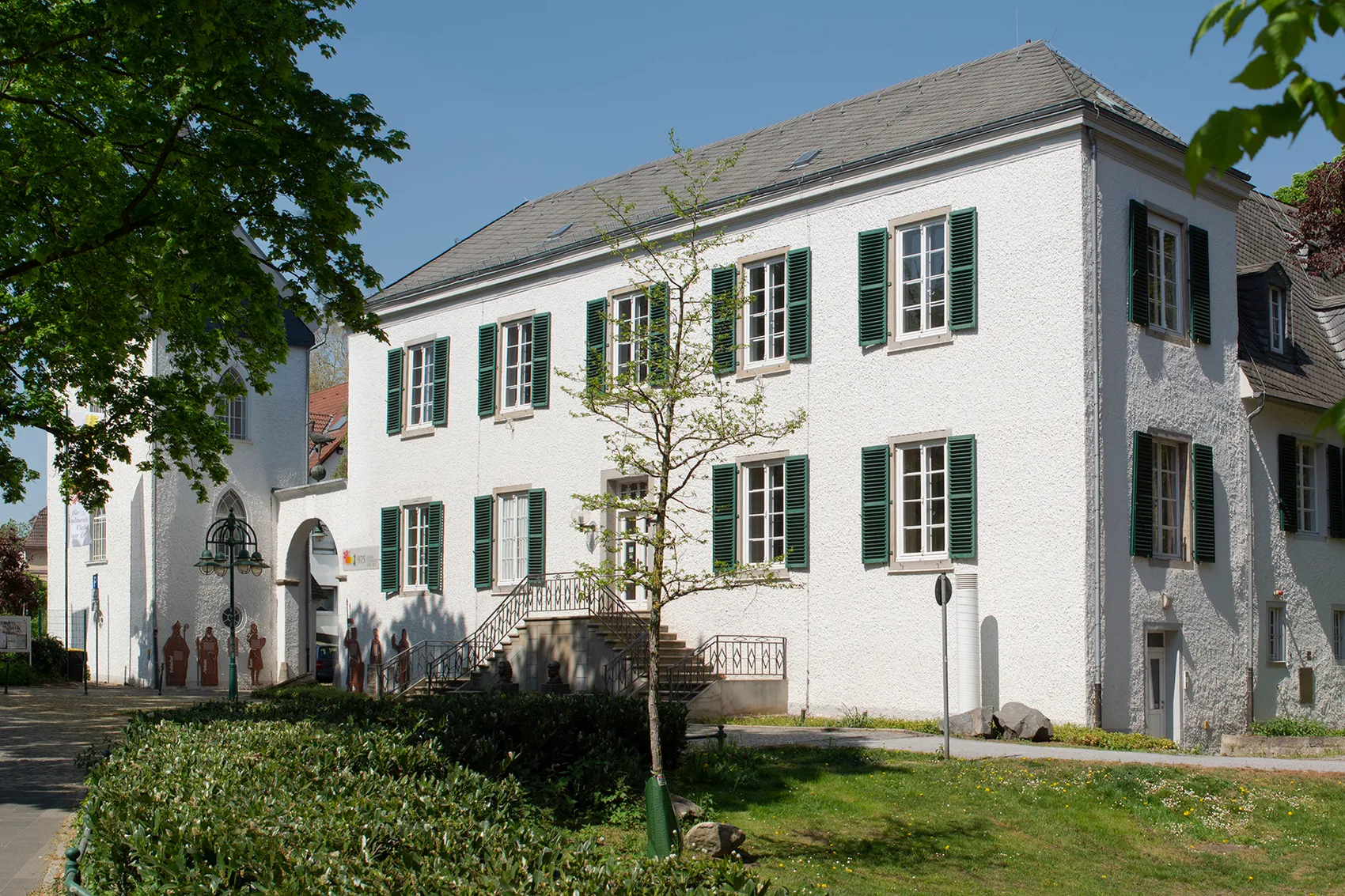 Das zweistöckige, weiße Haus Letmathe mit grünen Fensterläden und einer Treppe zum Eingang.