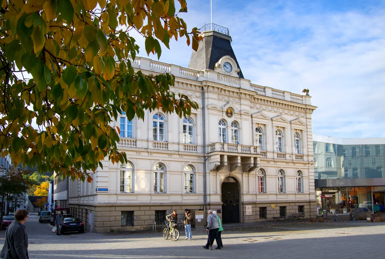 Das weiße Rathaus von Iserlohn mit Uhrturm an einem öffentlichen Platz.