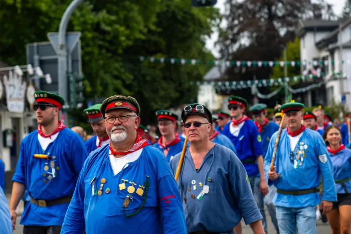 Mitglieder der Meinerzhagener Schützengilde in blauen Hemden und roten Halstüchern bei einem Umzug.