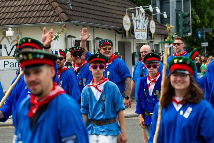 Mitglieder der Meinerzhagener Schützengilde in blauen Uniformen und roten Halstüchern bei einer Parade.