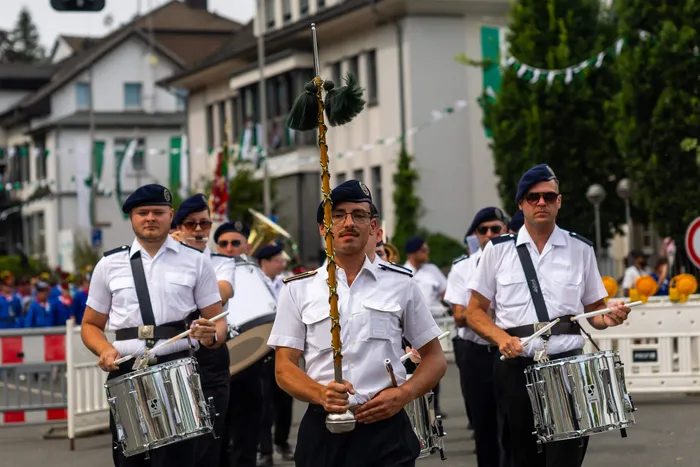 Mitglieder der Meinerzhagener Schützengilde in weißen Hemden und dunklen Baretten marschieren mit Trommeln und einem zeremoniellen Stab.