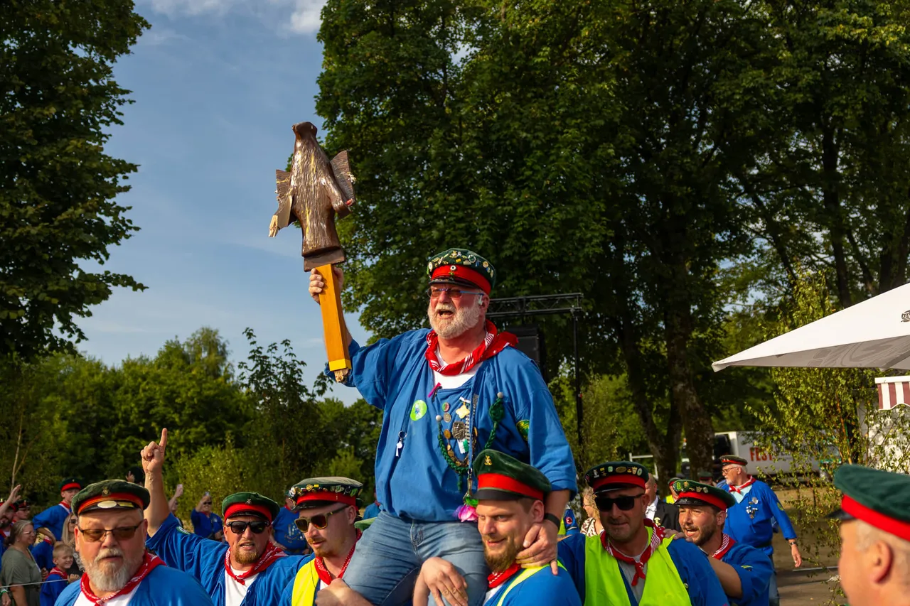 Stefan Schneider wird von Mitgliedern der Meinerzhagener Schützengilde auf den Schultern getragen und hält eine hölzerne Adlerstatue hoch.