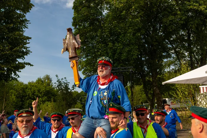 Stefan Schneider wird von Mitgliedern der Meinerzhagener Schützengilde auf den Schultern getragen und hält eine hölzerne Adlerstatue hoch.