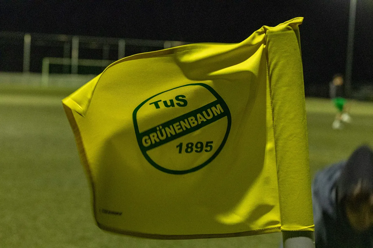 Gelbe Flagge mit dem grünen Vereinslogo des TuS Grünenbaum und der Gründungszahl 1895 weht im Wind.