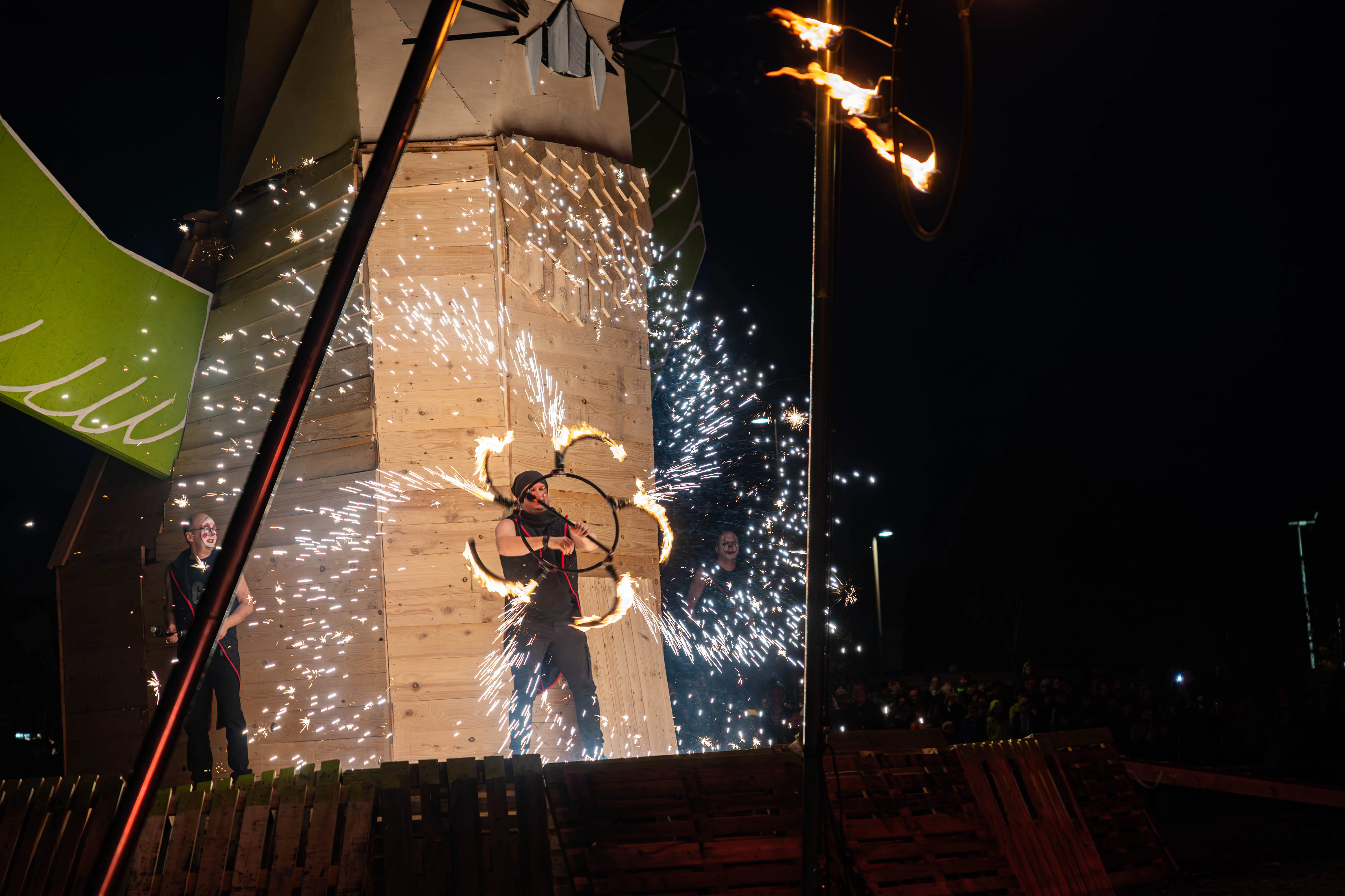 Zwei Feuerkünstler mit brennenden Reifen vor einer Holzkonstruktion bei einer Osterfeuer-Veranstaltung in Lüdenscheid.