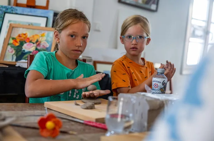 Zwei Mädchen sitzen an einem Tisch und arbeiten mit Ton bei einem Töpferkurs.