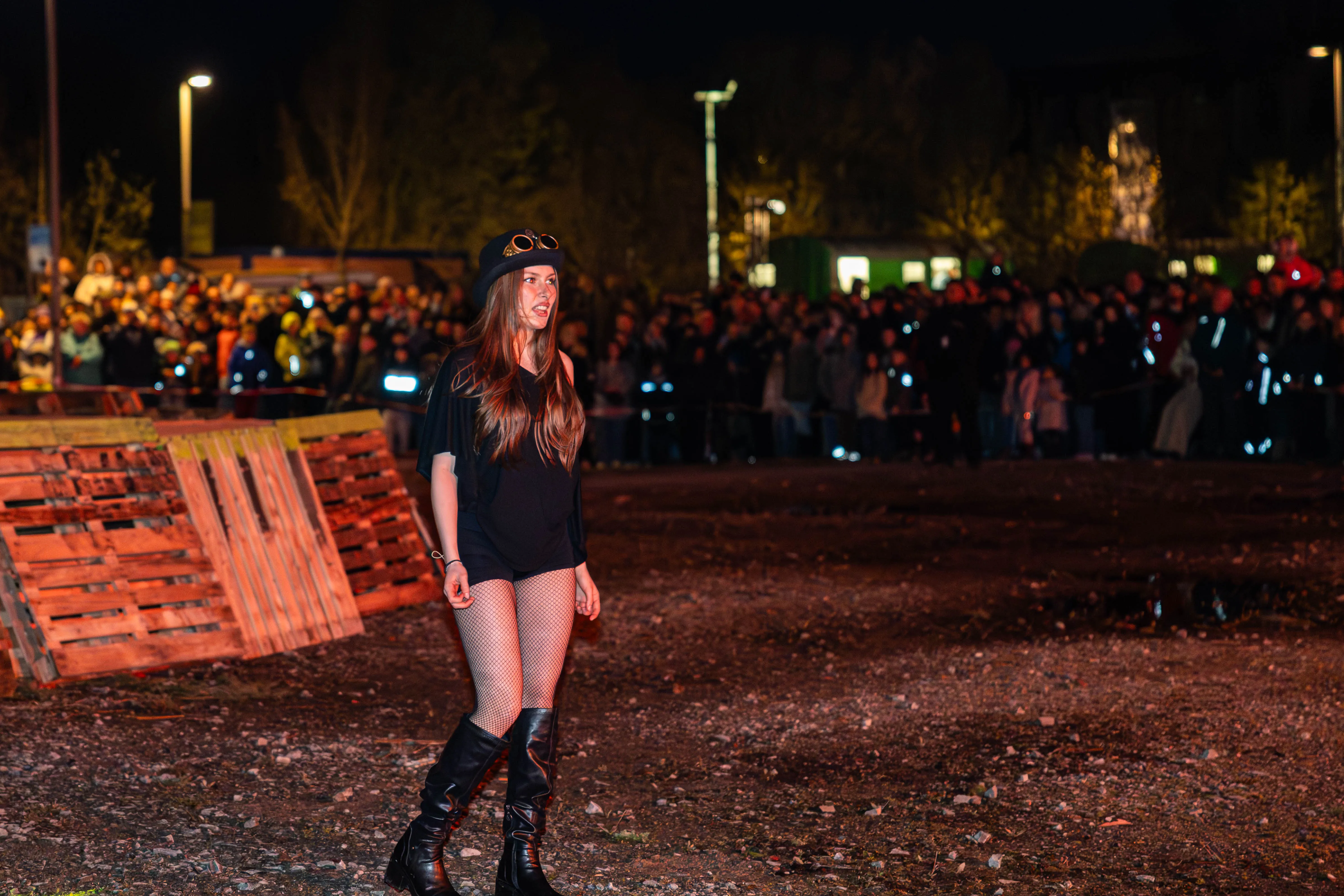 Junge Frau mit Steampunk-Brille und dunkler Kleidung steht vor einer großen Menschenmenge bei einem Osterfeuer in Lüdenscheid.