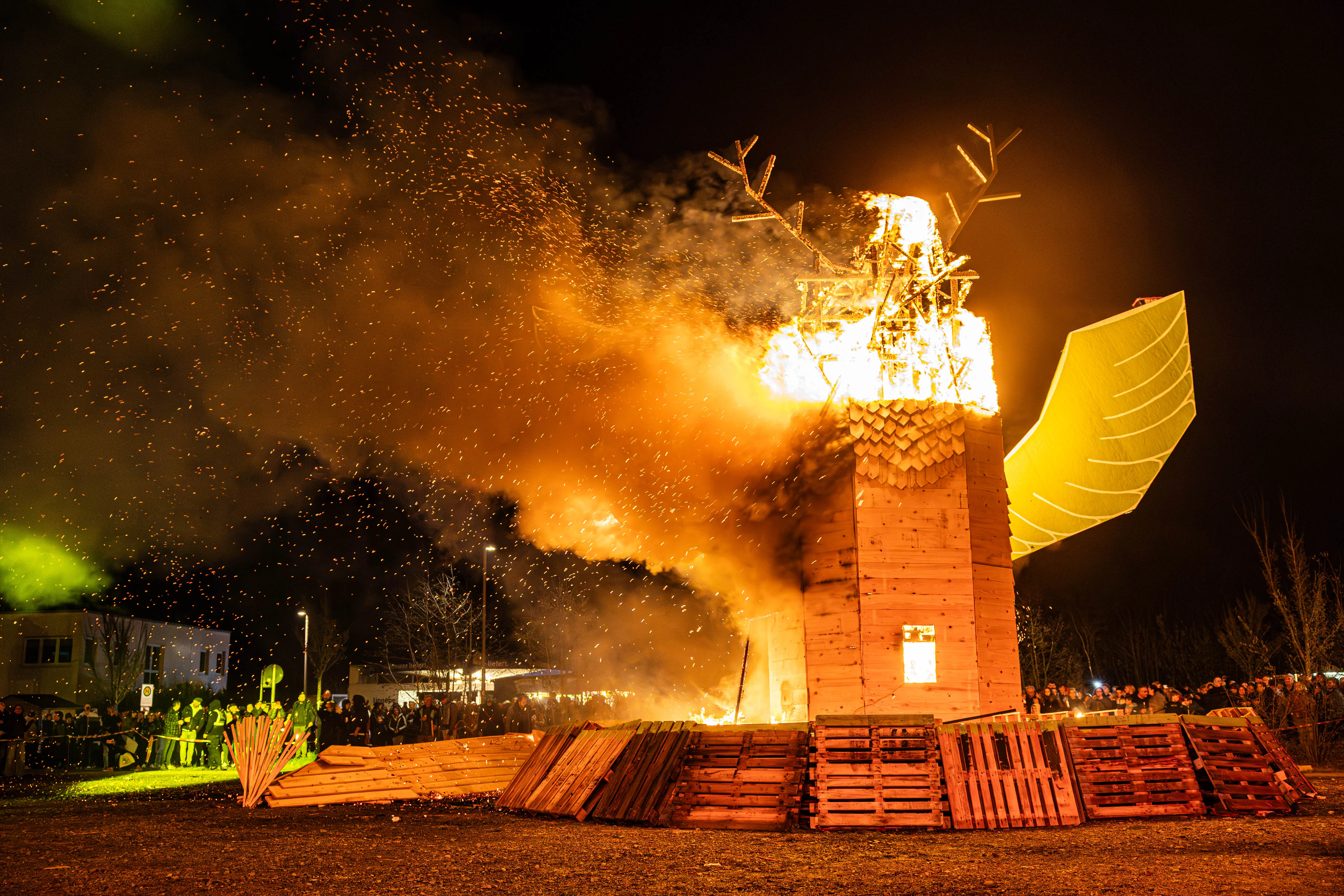 Großes Osterfeuer in Form eines stilisierten Fuchses brennt lichterloh, umgeben von zahlreichen Zuschauern in der Nacht.