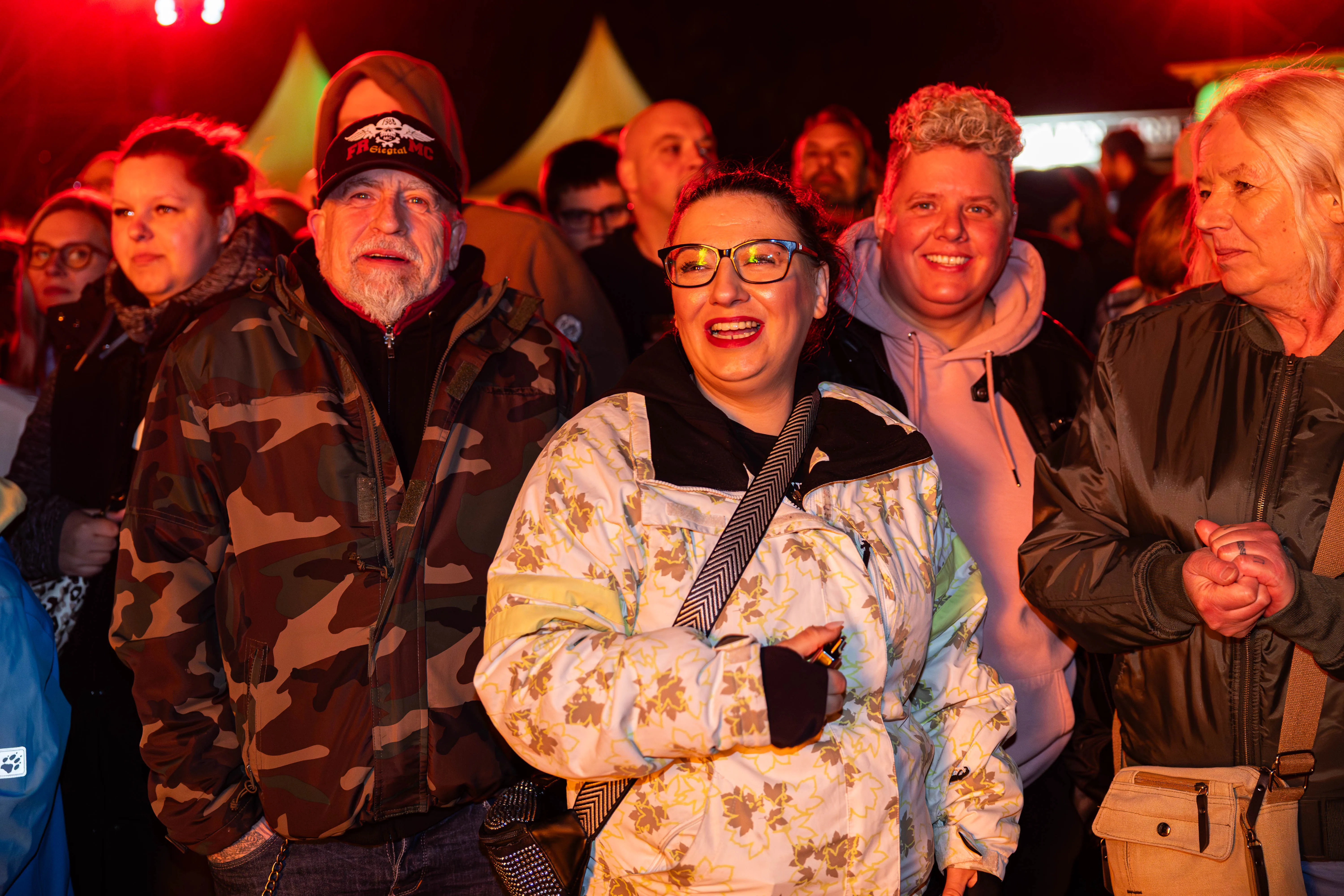 Freudige Menschenmenge vor einem Osterfeuer in Lüdenscheid. Eine Frau mit Brille lacht in die Kamera, während ein Mann neben ihr den Mund geöffnet hat.