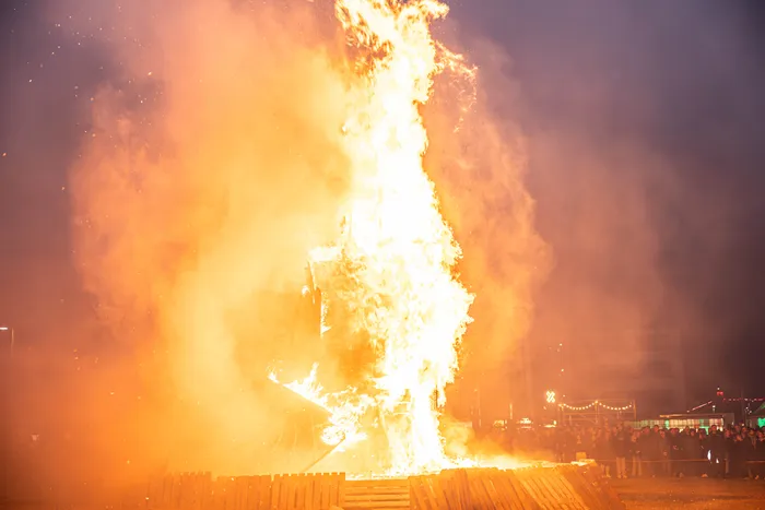 Hohes Osterfeuer mit lodernden Flammen und Funkenflug vor einer Menschenmenge in der Dunkelheit.
