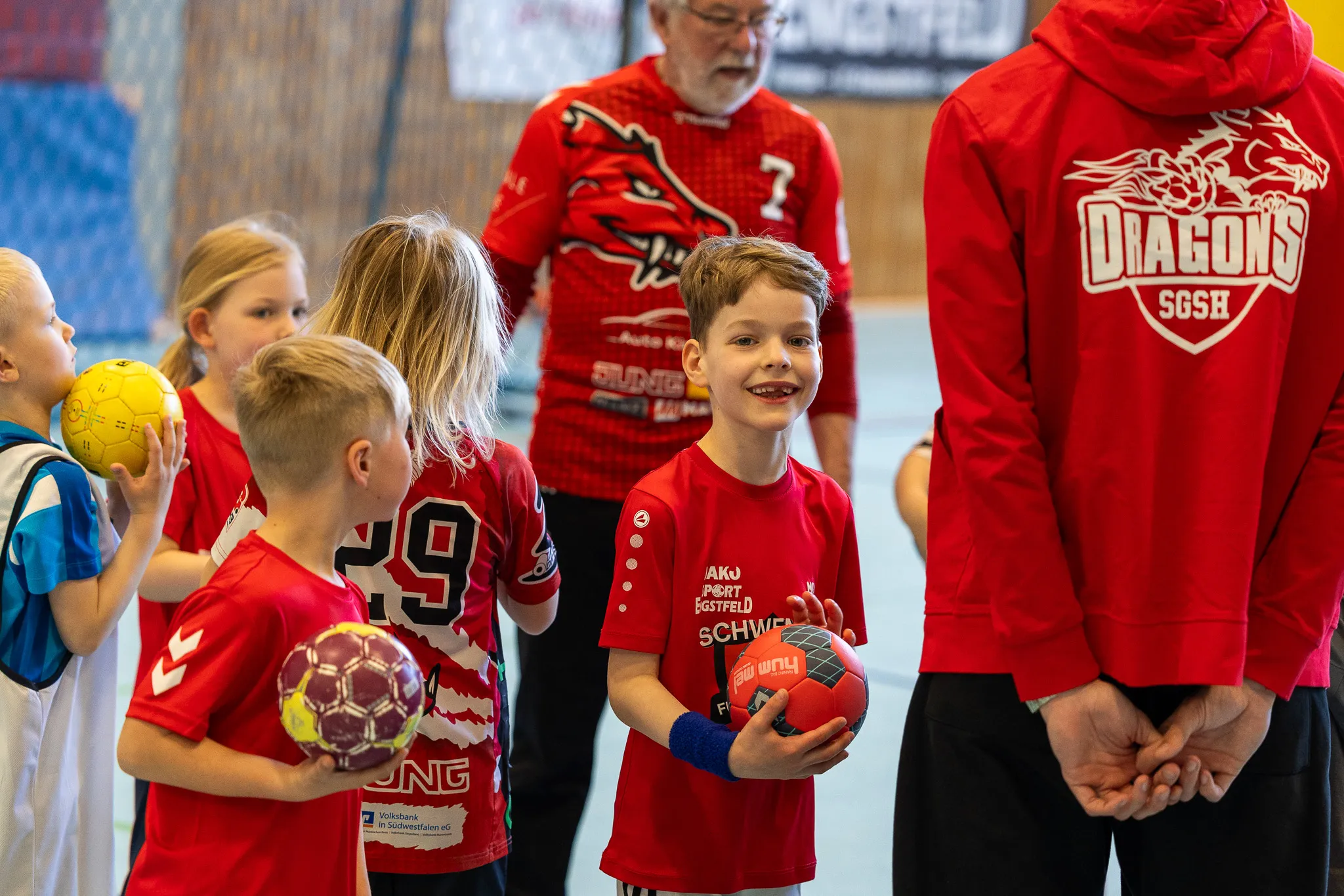 Jungen und Mädchen im Handballtraining mit Ball, einige tragen rote Trikots mit dem Aufdruck „Dragons SGSH“.