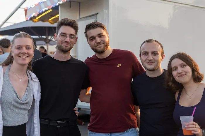 Fünf junge Menschen posieren lächelnd für ein Gruppenfoto bei der Q-Stall-Party.