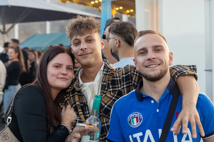 Drei lächelnde junge Menschen posieren eng beieinander bei der Q-Stall-Party in Schalksmühle.