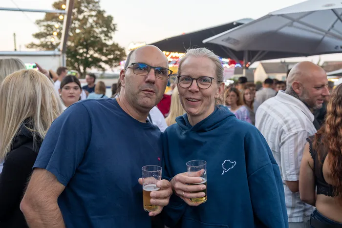 Ein Mann und eine Frau halten Gläser mit Bier bei der zehnten Q-Stall-Party in Schalksmühle.