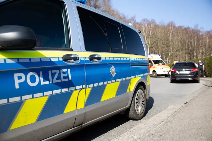 Polizeivan mit Aufschrift „POLIZEI“ steht am Straßenrand, im Hintergrund weitere Einsatzfahrzeuge und Personen.