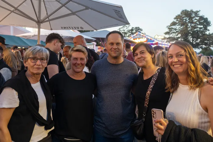 Fünf lächelnde Personen posieren unter einem Sonnenschirm bei der zehnten Q-Stall-Party in Schalksmühle.