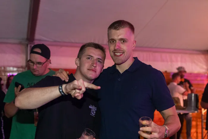 Zwei junge Männer posieren bei der zehnten Q-Stall-Party in Schalksmühle; einer zeigt mit dem Finger in die Kamera.