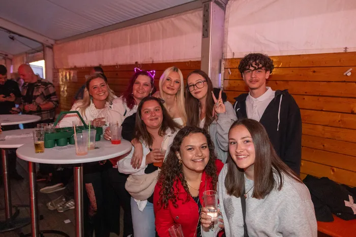 Eine Gruppe junger Menschen posiert lächelnd mit Getränken bei der Q-Stall-Party in Schalksmühle.