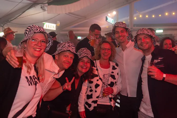 Eine Gruppe lachender Menschen mit Zebra-Hüten posiert bei der zehnten Q-Stall-Party in Schalksmühle.