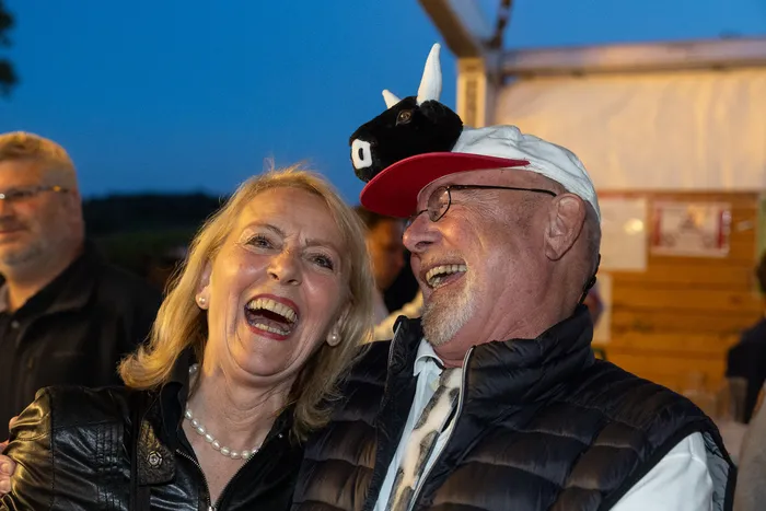 Eine lachende Frau und ein Mann mit einem schwarzen Tierhut und einer roten Kappe bei der Q-Stall-Party.