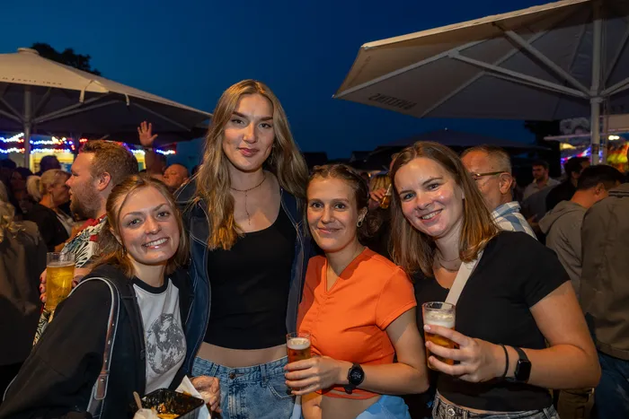 Vier lächelnde junge Frauen halten Getränke bei der Q-Stall-Party in Schalksmühle.