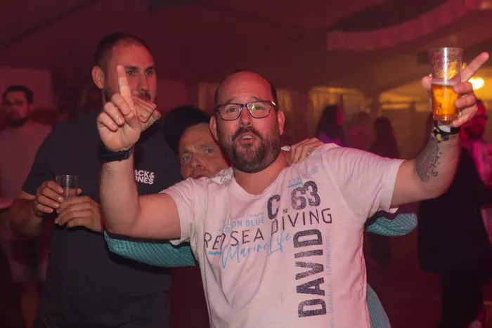 Ein Mann mit Brille und Bart hebt ein Glas Bier in die Höhe bei der Q-Stall-Party in Schalksmühle.