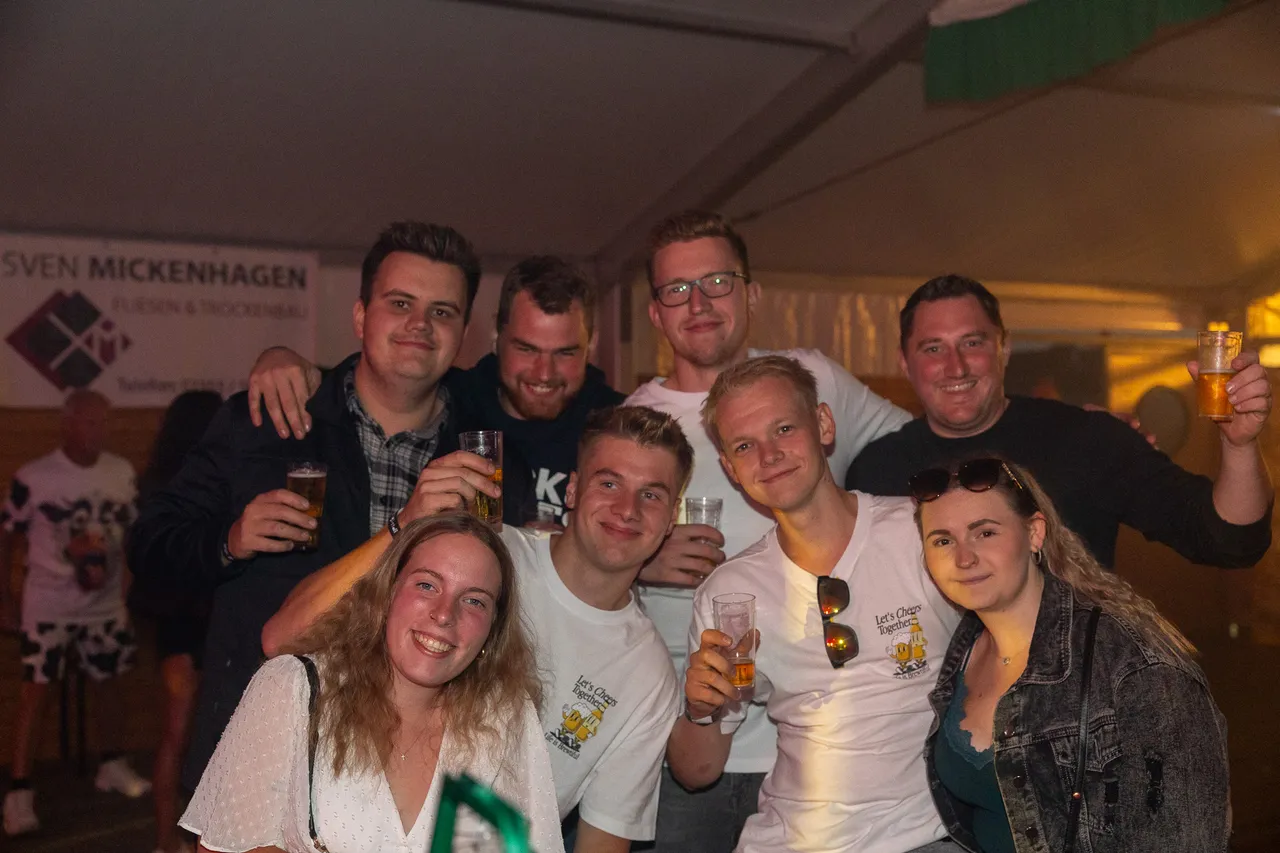 Eine Gruppe lächelnder junger Menschen hält Getränke bei der Q-Stall-Party in Schalksmühle.