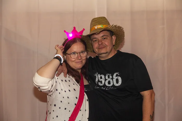 Eine Frau mit rosa Leuchtkrone und ein Mann mit Strohhut posieren gemeinsam bei der Q-Stall-Party.