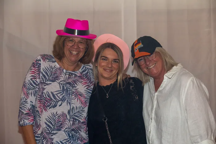 Drei lächelnde Frauen mit bunten Hüten posieren bei der zehnten Q-Stall-Party in Schalksmühle.