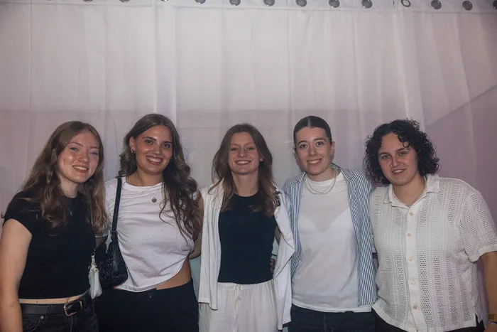 Fünf lächelnde junge Frauen posieren vor einem weißen Vorhang bei der Q-Stall-Party.