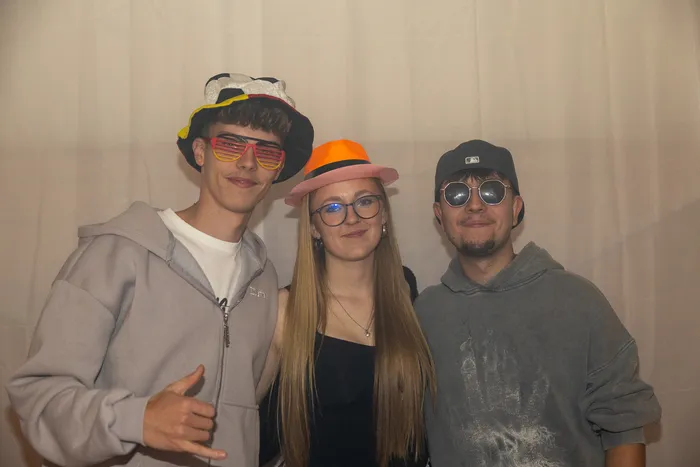 Drei junge Gäste mit bunten Hüten und Sonnenbrillen posieren bei der Q-Stall-Party.