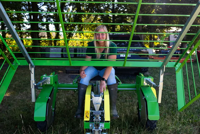 Eine Frau sitzt auf einer grünen landwirtschaftlichen Maschine zur Aussaat im Freien.
