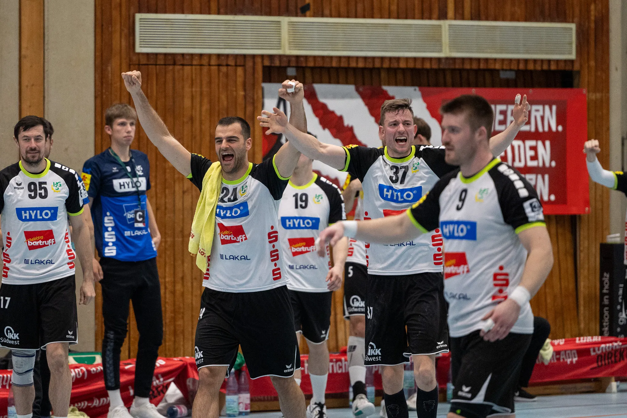 Handballspieler der SGSH Dragons feiern mit erhobenen Armen, trotz der Niederlage gegen den Tabellenführer.