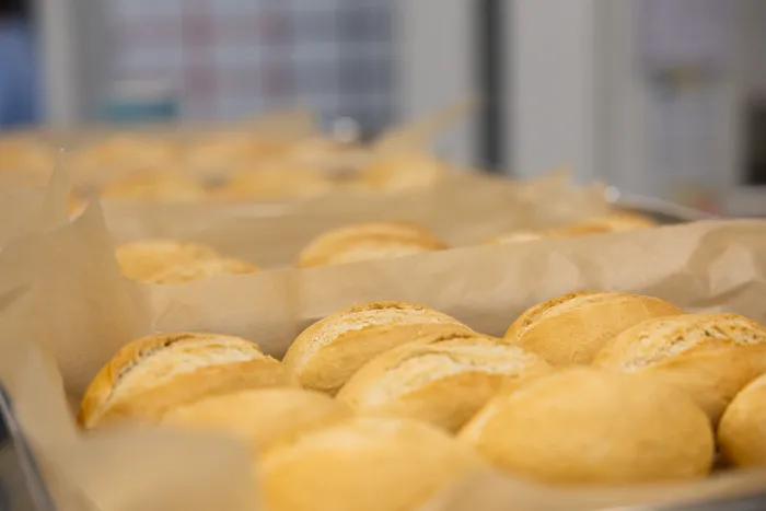 Goldbraune Brötchen in einer mit Backpapier ausgelegten Backform.