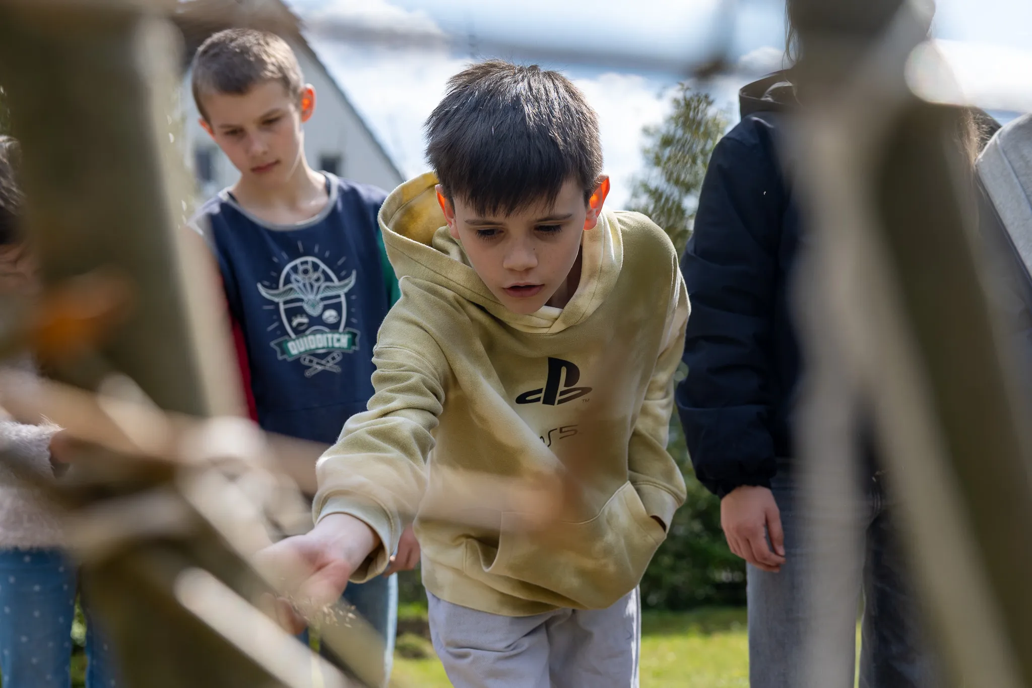 Zwei Jungen betrachten konzentriert ein kleines Beet mit Pflanzen. Einer trägt einen Hoodie mit Playstation-Logo.