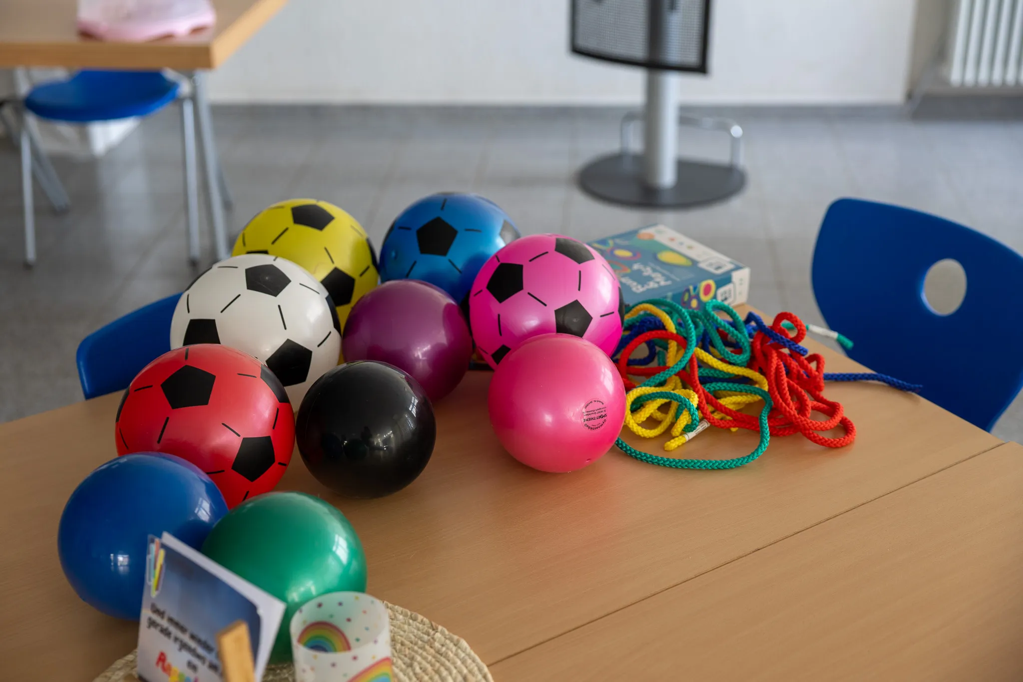 Bunte Bälle und Springseile liegen auf einem Tisch, bereit für den Sportunterricht oder die Pause.