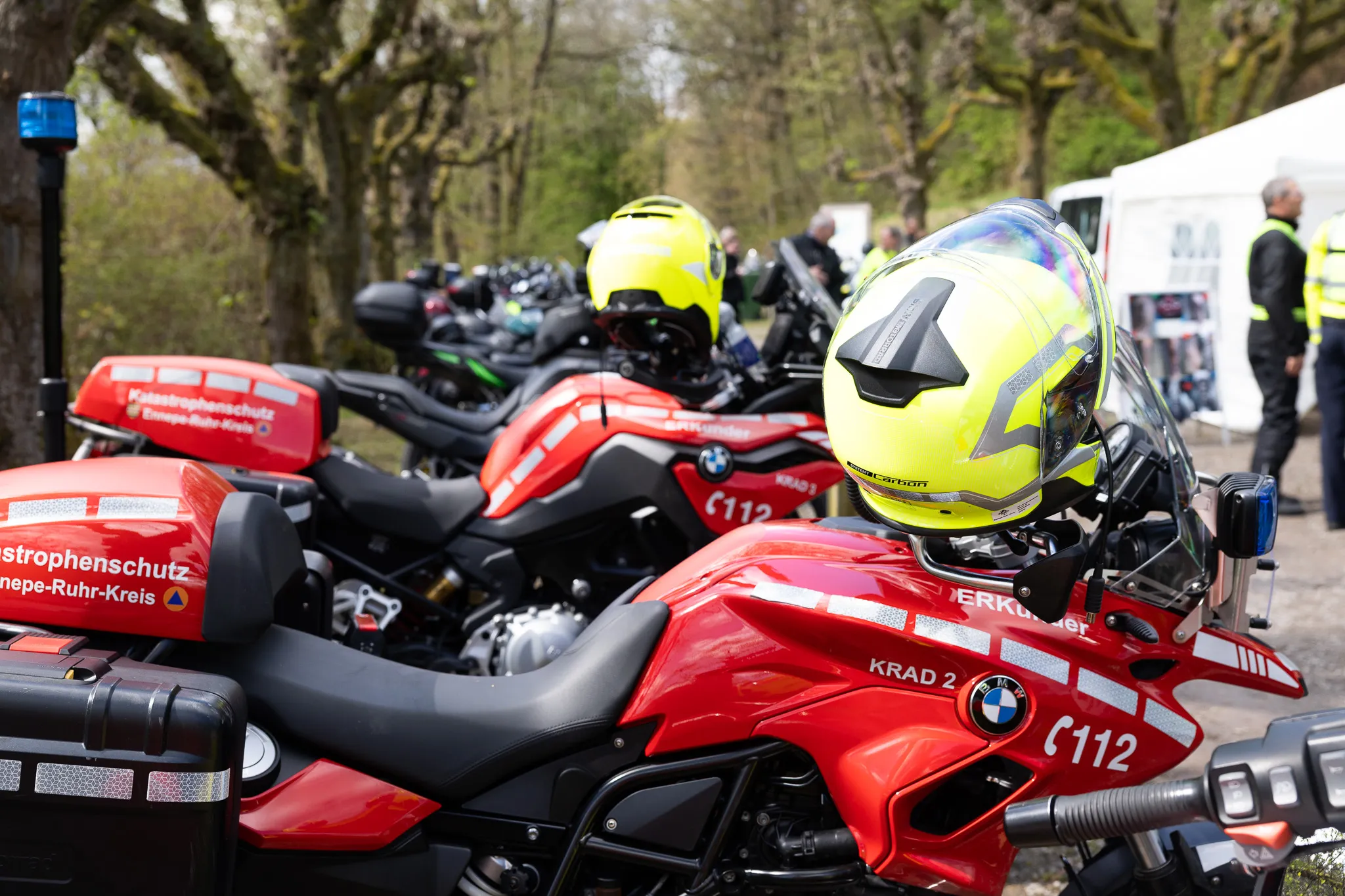 Mehrere rote Motorräder der Polizei mit Blaulicht und der Aufschrift „Katastrophenschutz“ stehen im Freien, ein Motorradhelm liegt auf dem Tank eines Motorrads.