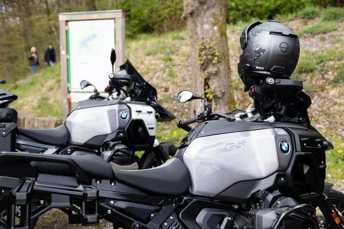 Zwei geparkte Motorräder der Marke BMW mit umfangreichem Zubehör stehen im Vordergrund, auf dem Soziussitz eines Motorrads ist ein Helm platziert.