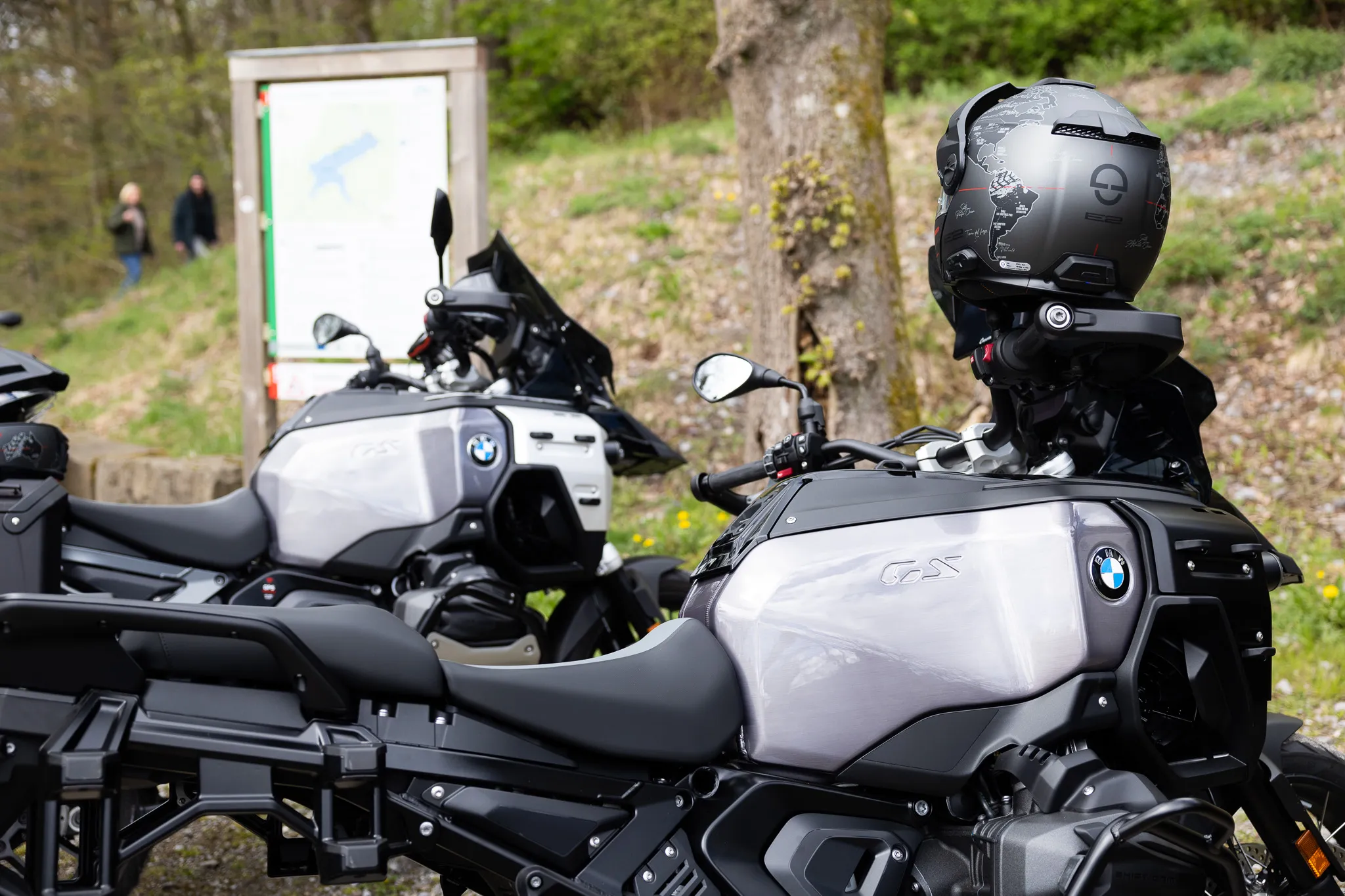 Zwei geparkte Motorräder der Marke BMW mit umfangreichem Zubehör stehen im Vordergrund, auf dem Soziussitz eines Motorrads ist ein Helm platziert.