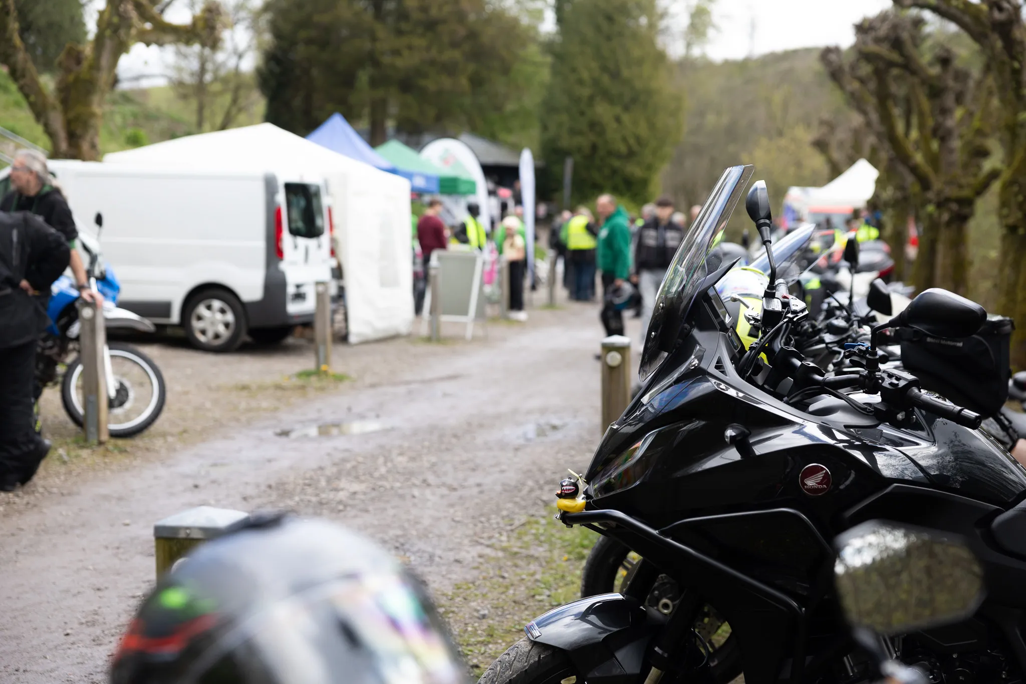 Motorrad mit Honda-Logo im Vordergrund, im Hintergrund Menschengruppe und Zelte einer Präventionsveranstaltung der Polizei.