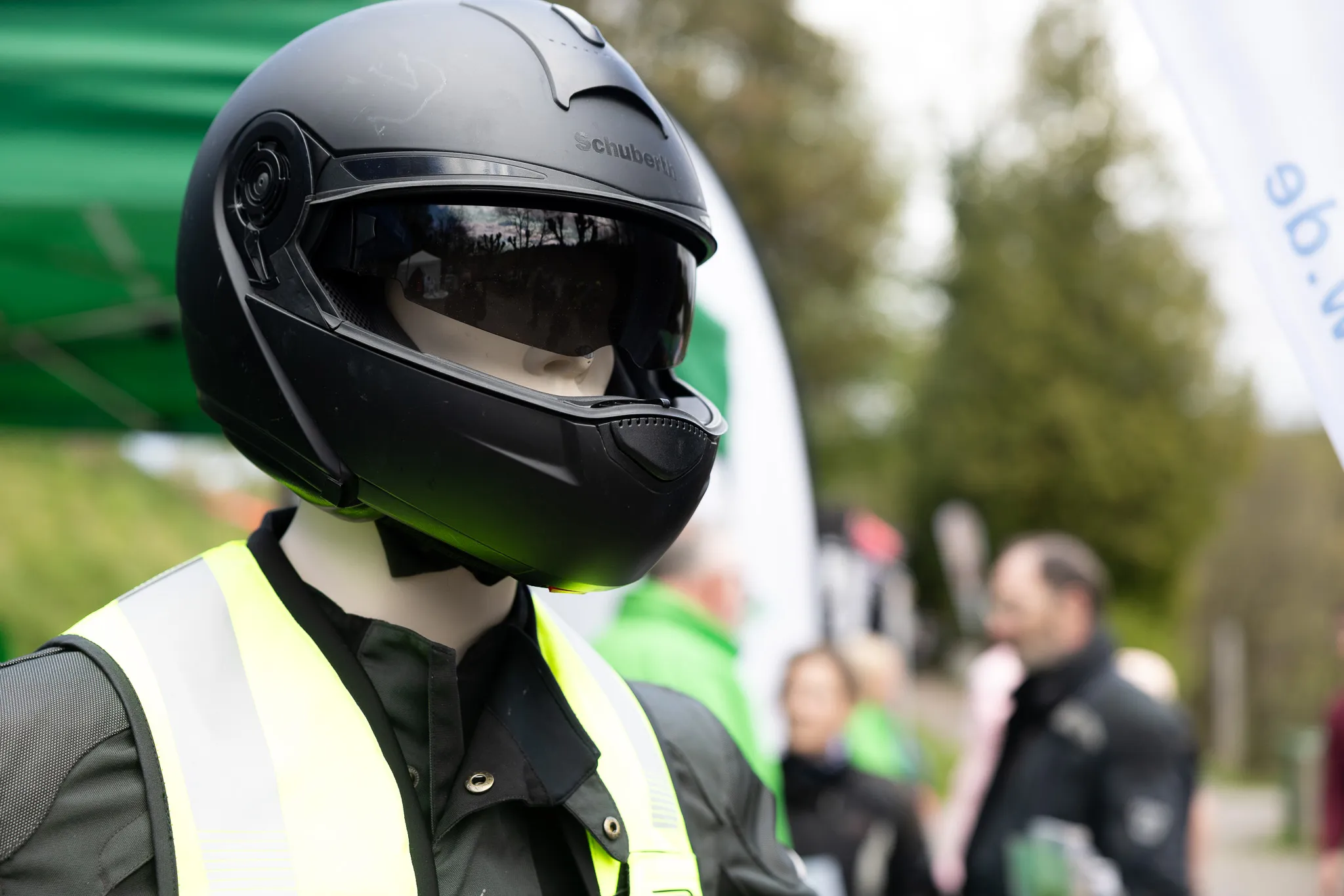 Polizist mit schwarzem Motorradhelm und Reflektorweste steht vor verschwommenem Hintergrund.