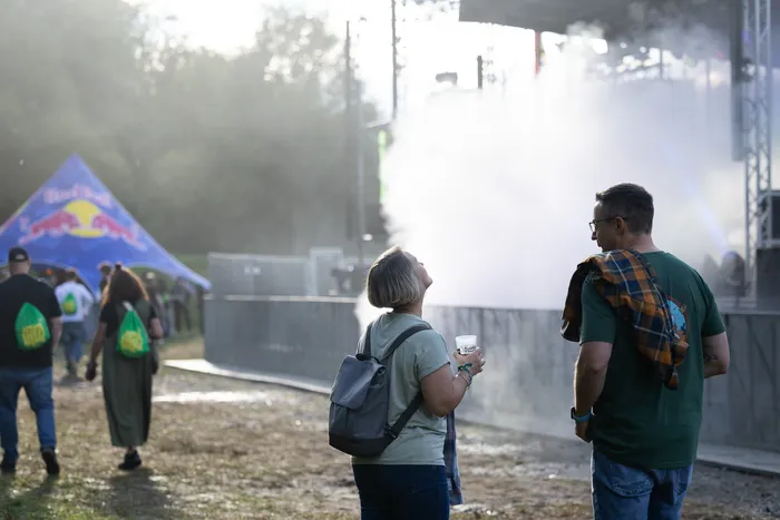 Besucher blicken bei einem Musikfestival auf eine Bühne, die in dichten weißen Nebel gehüllt ist. Im Hintergrund ist ein blaues Red Bull Zelt zu sehen.