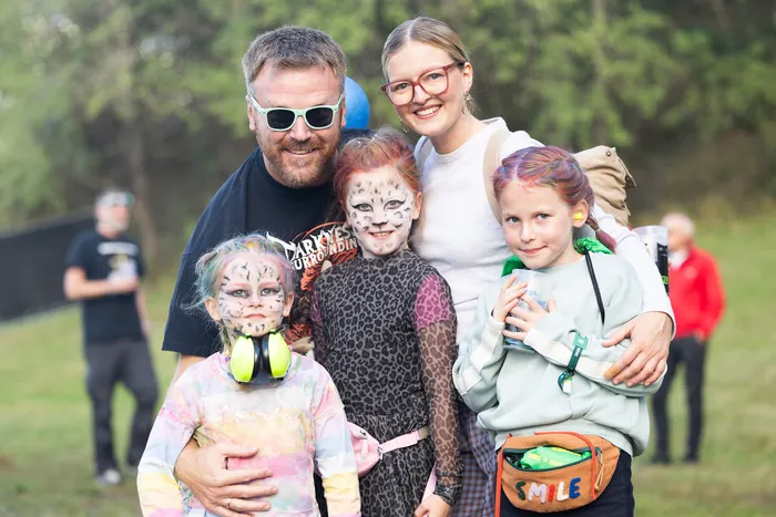 Ein Mann, eine Frau und drei Kinder mit Gesichtsbemalung posieren gemeinsam im Freien.