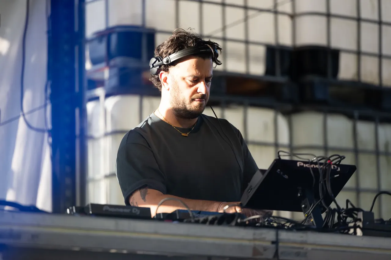 DJ Disco Danny mit Kopfhörern beim Auflegen an einem Mischpult.