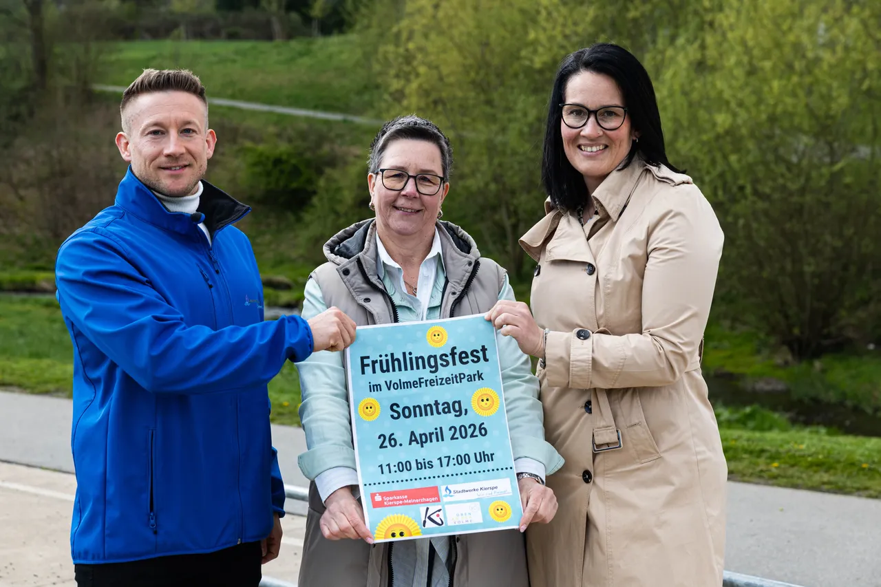 Drei Personen halten ein Werbeschild für das Frühlingsfest im VolmeFreizeitPark am 26. April 2026. Das Schild zeigt die Zeit von 11:00 bis 17:00 Uhr und Logos der Stadtwerke Kierspe und Sparkasse Kierspe-Meinerzhagen.
